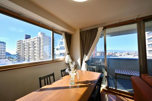 a dining room with a table and large windows at コングラッツ湘南 in Fujisawa
