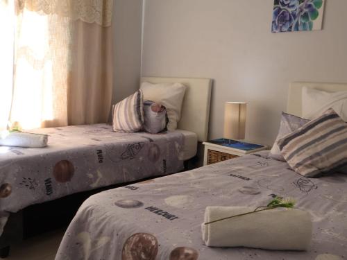 SerenShell House في Stompneusbaai: غرفة نوم بها سريرين ونافذة