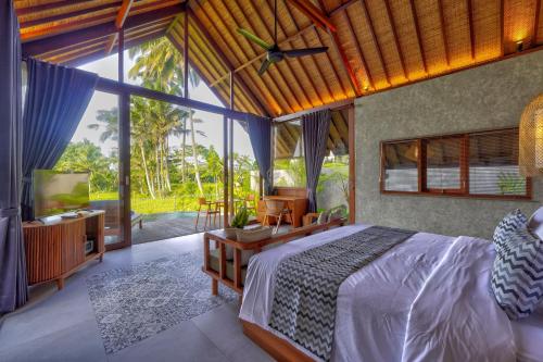 a bedroom with a bed and a large window at The Udiana Ubud in Tegalalang