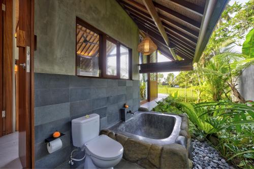 a bathroom with a toilet and a bath tub at The Udiana Ubud in Tegalalang