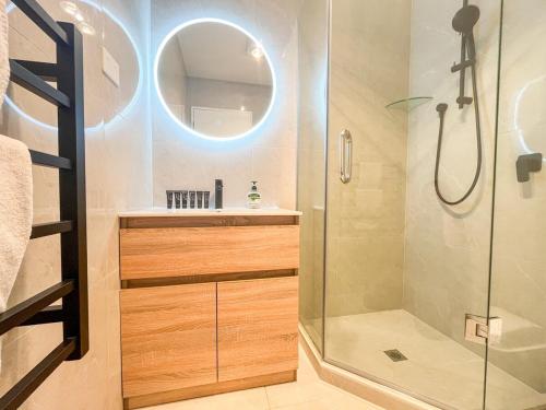 a bathroom with a shower and a sink and a mirror at Brand-New 5BR Retreat, Space & Serenity by Nature in Auckland