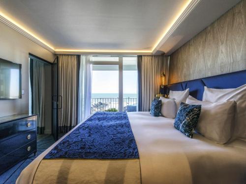 sypialnia z dużym łóżkiem i dużym oknem w obiekcie La Grande Terrasse Hotel & Spa La Rochelle - MGallery Collection w mieście Châtelaillon-Plage
