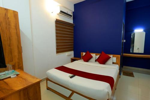 een slaapkamer met een bed met rode kussens en een blauwe muur bij Calicut residency in Kozhikode
