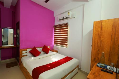 een slaapkamer met roze muren en een bed met rode kussens bij Calicut residency in Kozhikode