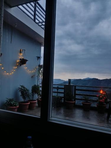 a window with a view of a balcony with plants at Mountain and peace in Shimla