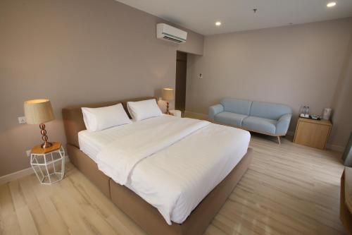 a bedroom with a large bed and a blue chair at D'Anggerek Serviced Apartment in Bandar Seri Begawan