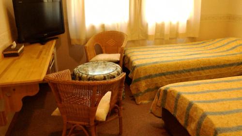 a hotel room with two beds and a desk and a television at Pension Come in Minami Uonuma