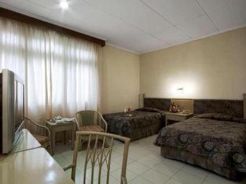 pokój hotelowy z dwoma łóżkami i kanapą w obiekcie Hotel Griyadi Kusuma Sahid w mieście Surakarta