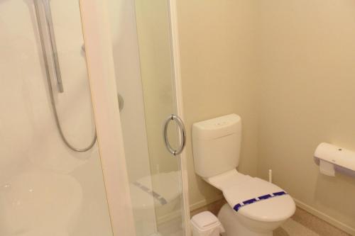 a bathroom with a toilet and a glass shower at Sunset Motel in Fox Glacier