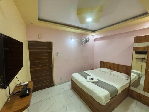 a bedroom with a bed with a television and a desk at Mandara Comforts Hotel in Bengaluru
