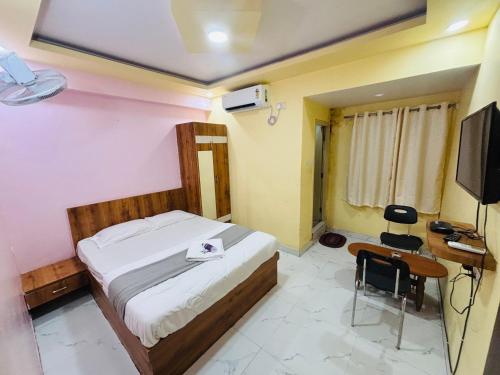 a bedroom with a bed and a desk and a television at Mandara Comforts Hotel in Bengaluru