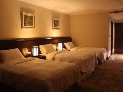 a hotel room with three beds in a room at Chong Yu Hotel in Taoyuan