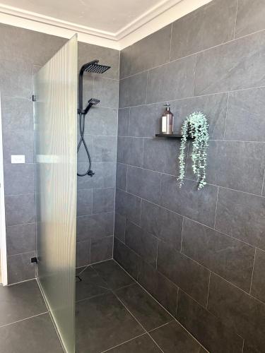 a shower with a glass door in a bathroom at 2 Bedroom Coastal getaway with ocean views! in Port Macquarie