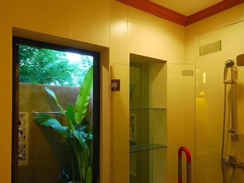 un bagno con doccia e una porta a vetri con una pianta di Phu View Resort Khao Yai a Ban Nong Ka Cha