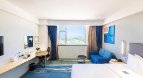 a hotel room with a bed and a blue couch at Holiday Inn Express Zhangye By IHG in Zhangye
