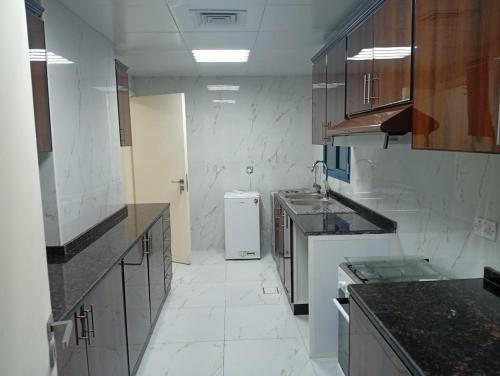 Big Studio In Abu Dhabi Corniche في أبوظبي: مطبخ مع حوض وثلاجة