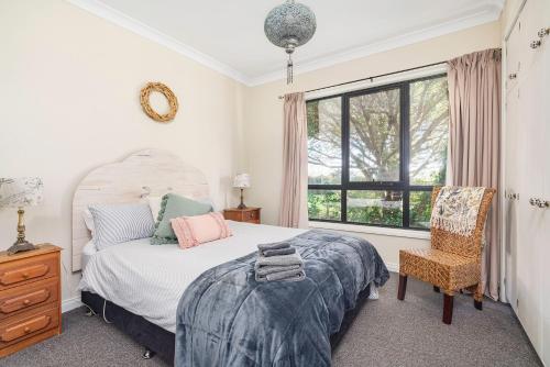a bedroom with a bed and a chair and a window at Farmhouse on the Cradle Coast Forth in Forth