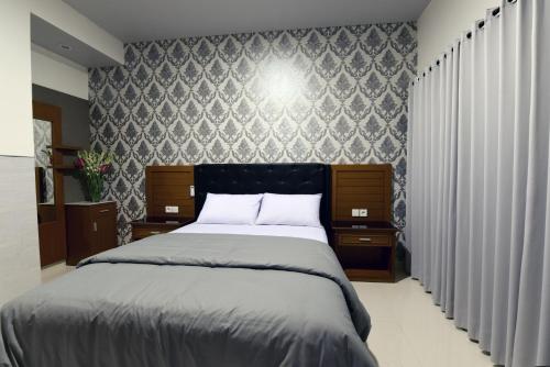 a bedroom with a large bed and a wall at Le Lima in Kuta