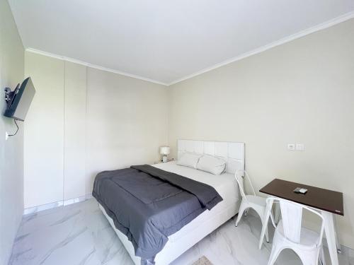 a white bedroom with a bed and a table at The Lavana Kubu Be Long Sanur in Sanur