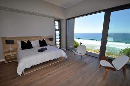 a bedroom with a bed and a view of the beach at Cliffhanger Estate in Keurboomstrand