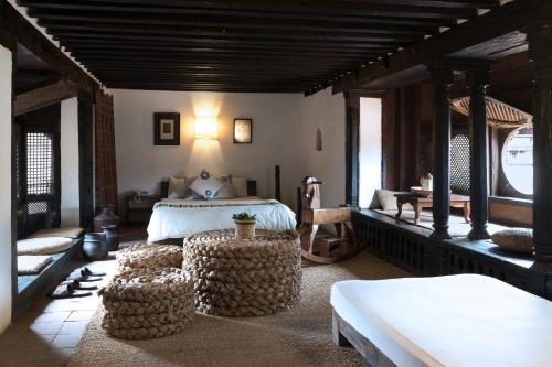 a bedroom with a bed and two ottomans at Peacock Guest House in Bhaktapur