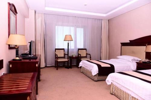 a hotel room with two beds and a table and chairs at Heilongjiang Kunlun Hotel in Harbin