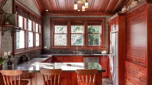 a kitchen with wooden cabinets and a island with bar stools at Mt Eden Victorian Villa in Auckland