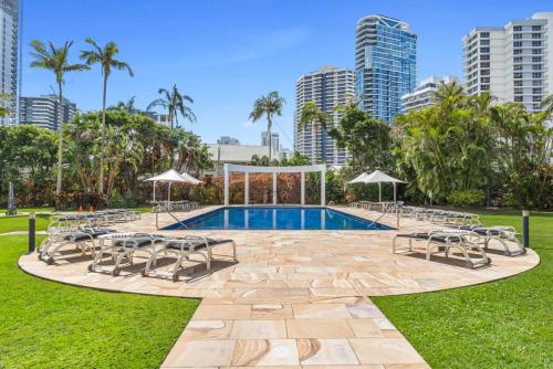 a swimming pool in a park with chairs and umbrellas at Luxury 3BR Gold Coast Stay Ocean and City Views in Gold Coast