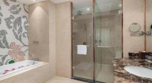 a bathroom with a shower and a tub and a sink at Howard Johnson Zunyue Hotel Chengdu in Chengdu