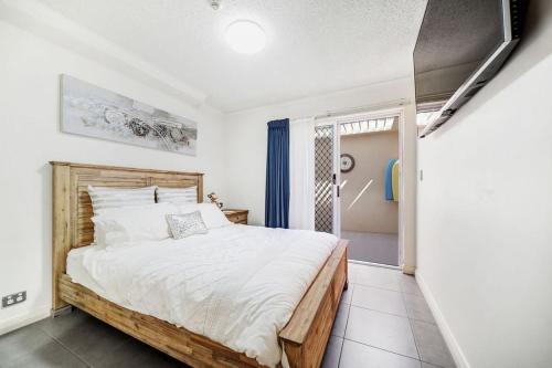 Un dormitorio con una cama y una puerta corrediza de vidrio. en Poolside Escape at Alexandra Headland, en Alexandra Headland