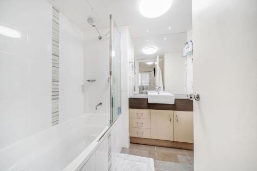Un baño blanco con ducha y lavabo. en Poolside Escape at Alexandra Headland, en Alexandra Headland