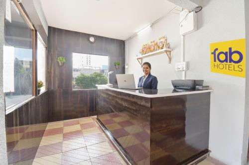 a woman sitting at a reception desk with a laptop at Via Diamond Inn in Pune