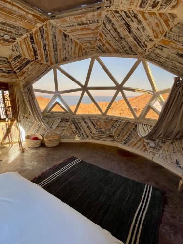 a room with a large window and a bed with a rug at Mannam desert dome in Dahab