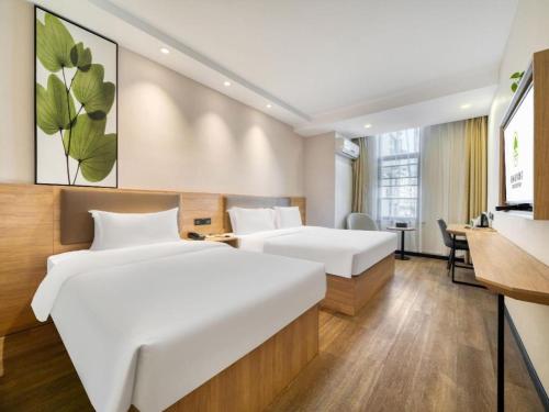 a hotel room with two beds and a desk at GreenTree Inn HuZhou AnJi YingBin Avenue Express Hotel in Huangshu