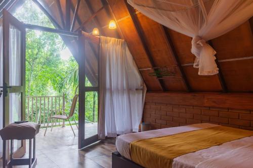 a bedroom with a bed in a room with a window at Green Forest Cabanas - Ella in Ella