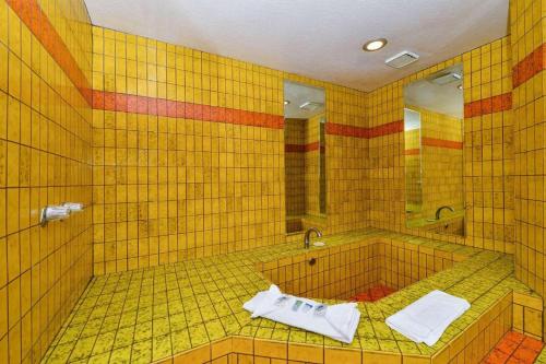 a yellow tiled bathroom with a tub and a mirror at Americas Best Value Inn & Suites Los Angeles Downtown SW in Los Angeles
