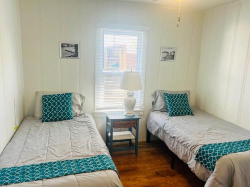 a room with two beds and a table with a lamp at Garden Cottage in Langley