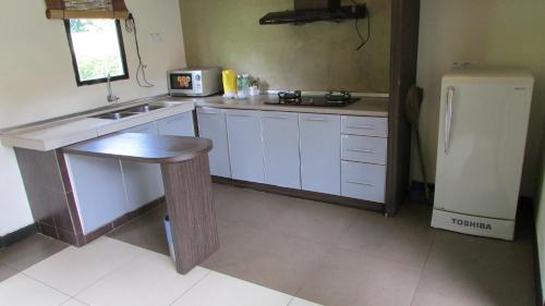 a kitchen with white cabinets and a sink and a refrigerator at Hotel Felda Residence Hot Springs in Sungkai