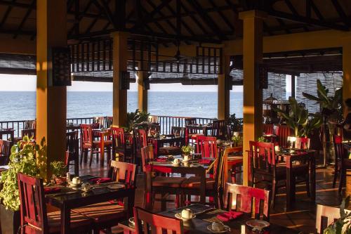 um restaurante com mesas e cadeiras com o oceano ao fundo em Victoria Phan Thiet Beach Resort & Spa em Mui Ne