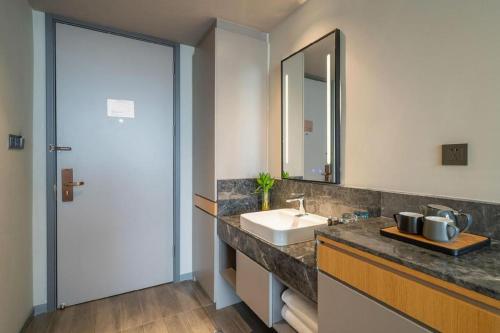 ein Badezimmer mit Waschbecken und Spiegel in der Unterkunft Home Inn Selected Xiamen University Zhongshan Road in Xiamen