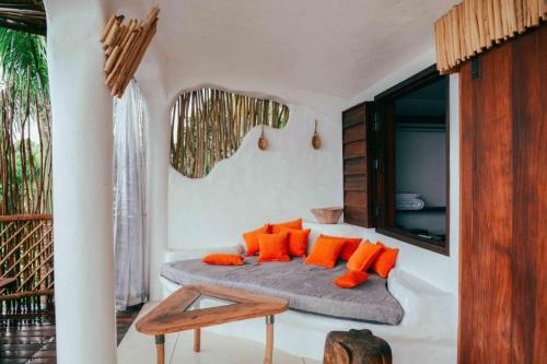 ein Wohnzimmer mit einem Sofa und orangefarbenen Kissen in der Unterkunft BambooJam Villa in La Ceiba