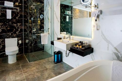 un bagno con lavandino, WC e doccia di Savero Hotel Depok a Depok