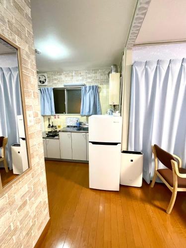 a kitchen with white cabinets and blue curtains at BlueHouse in Hiroshima