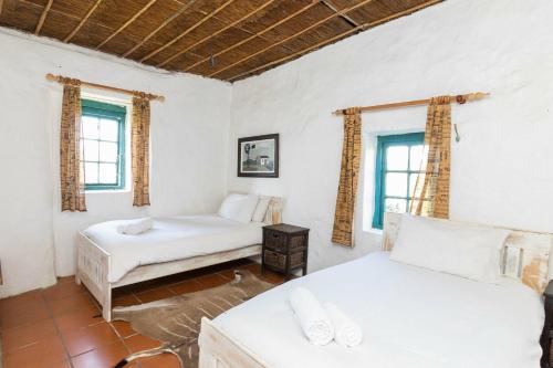 una stanza con due letti e due finestre di Die Jaghuisie at Blombosch Game Farm a Yzerfontein