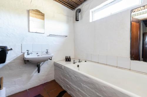un bagno con un lavandino, una vasca da bagno e un lavandino di Die Jaghuisie at Blombosch Game Farm a Yzerfontein
