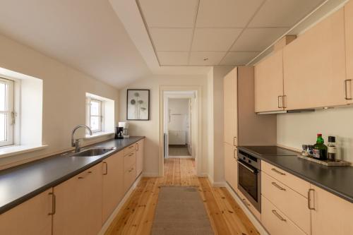 a kitchen with white cabinets and black appliances at Light-Filled 5BR Home Near Tivoli & Strøget for 12 in Copenhagen