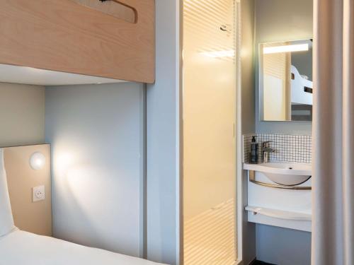 a small bedroom with a sink and a mirror at ibis budget Issy Les Moulineaux Paris Ouest in Issy-les-Moulineaux