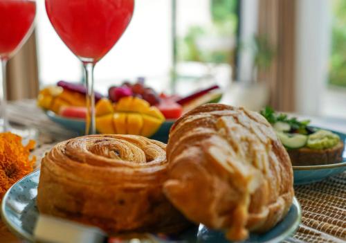 un tavolo con un piatto di prodotti da forno e un bicchiere di vino di Ubud Dzen Villa 3 ad Ubud