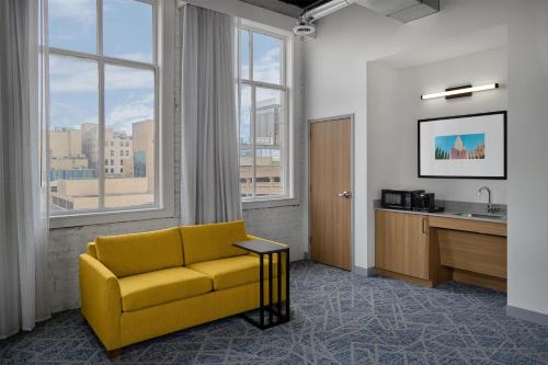 a living room with a yellow couch and a sink at Hampton Inn by Hilton Lincoln Downtown in Lincoln