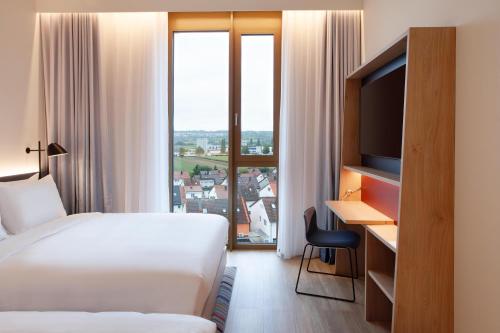a hotel room with a bed and a desk with a television at Hampton By Hilton Stuttgart Airport in Filderstadt
